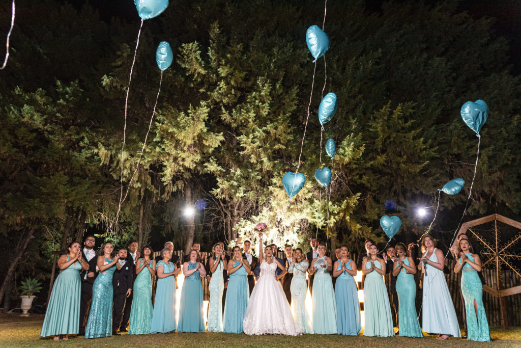 contrato de prestação de serviços fotográficos - noiva, padrinho e madrinhas posando para foto soltando balões de coração azul.