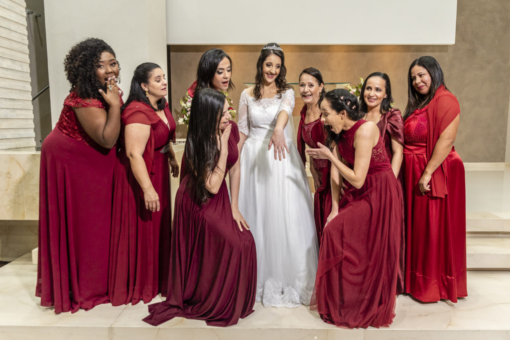 Noivas e madrinhas posando para foto com seus belos vestidos em tons de vermelho e confortáveis que estão entre os 11 itens indispensáveis para seu casamento.