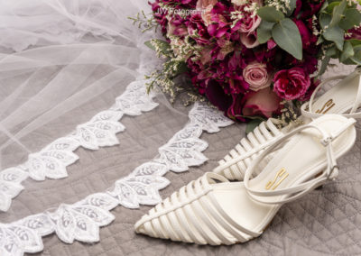 Inspirações para Festa de Casamento - Detalhes da barro do véu, sapato branco da noiva e um lindo buquê de flores na paleta da cor Viva Magenta.