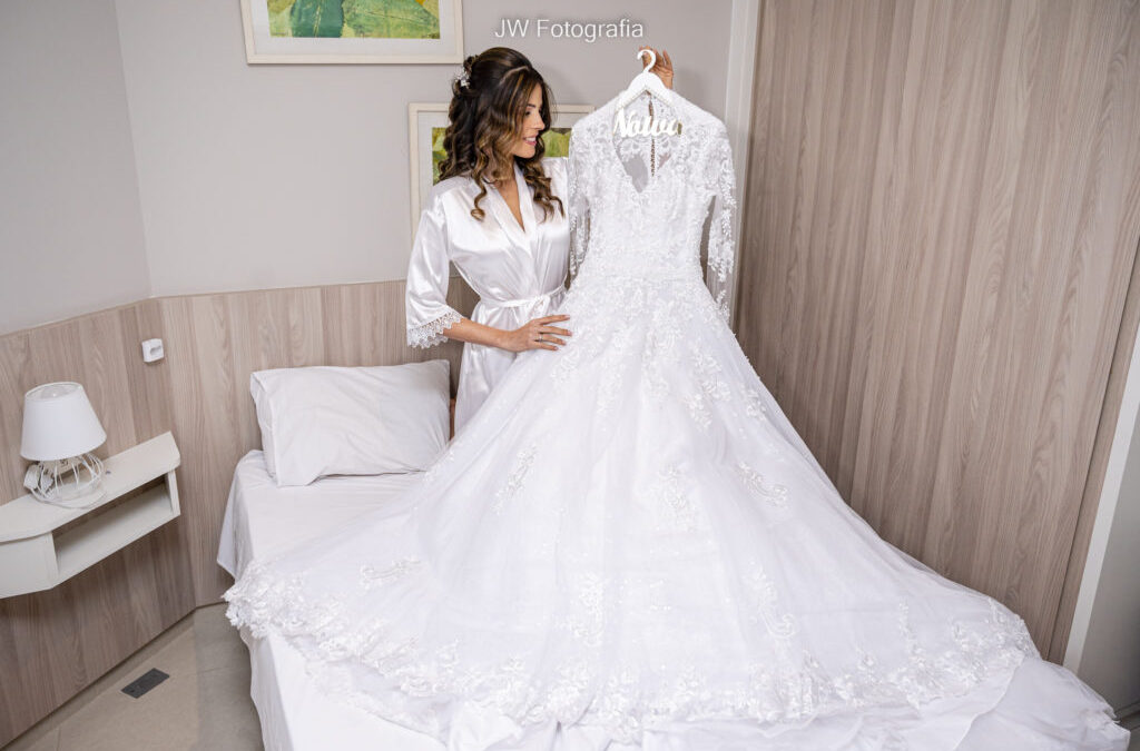 dicas de vestido de noiva ideal - Noiva encantada admirando o seu vestido.