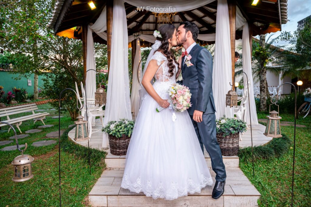 Casar no Jardim das Orquídeas - noivos se beijando com coreto e estilo rústico ao fundo.