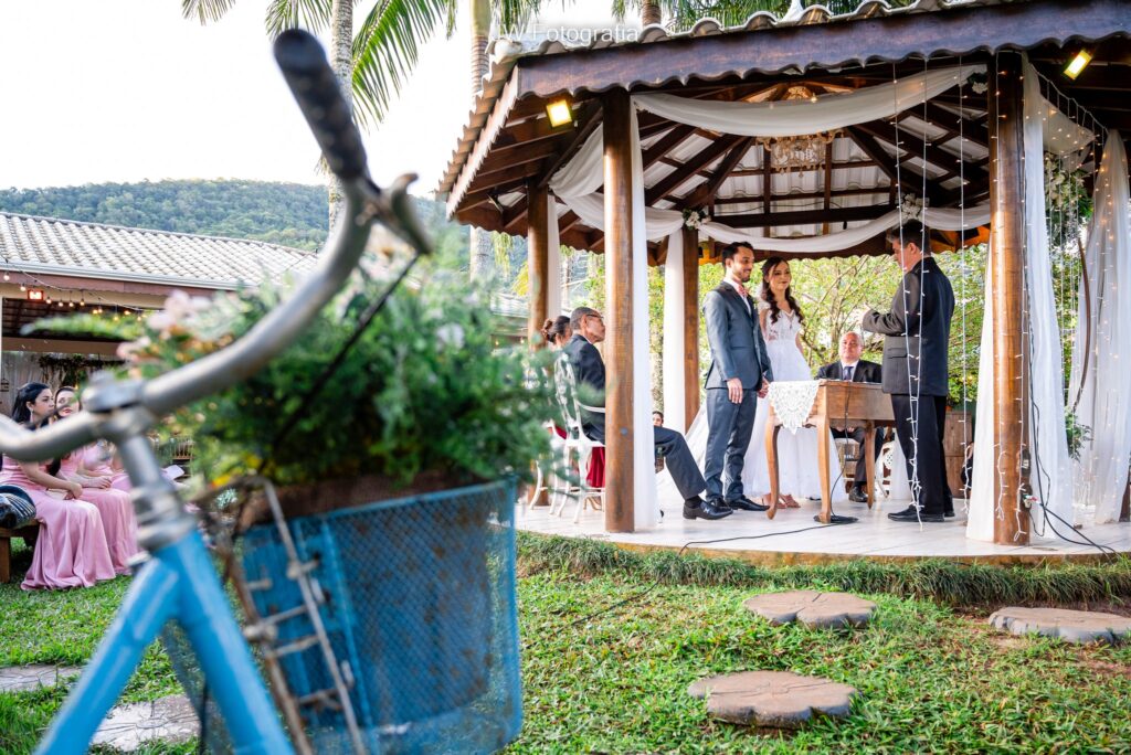 Casar no Jardim das Orquídeas - casamento ao fundo com bicicleta vintage azul no foco.