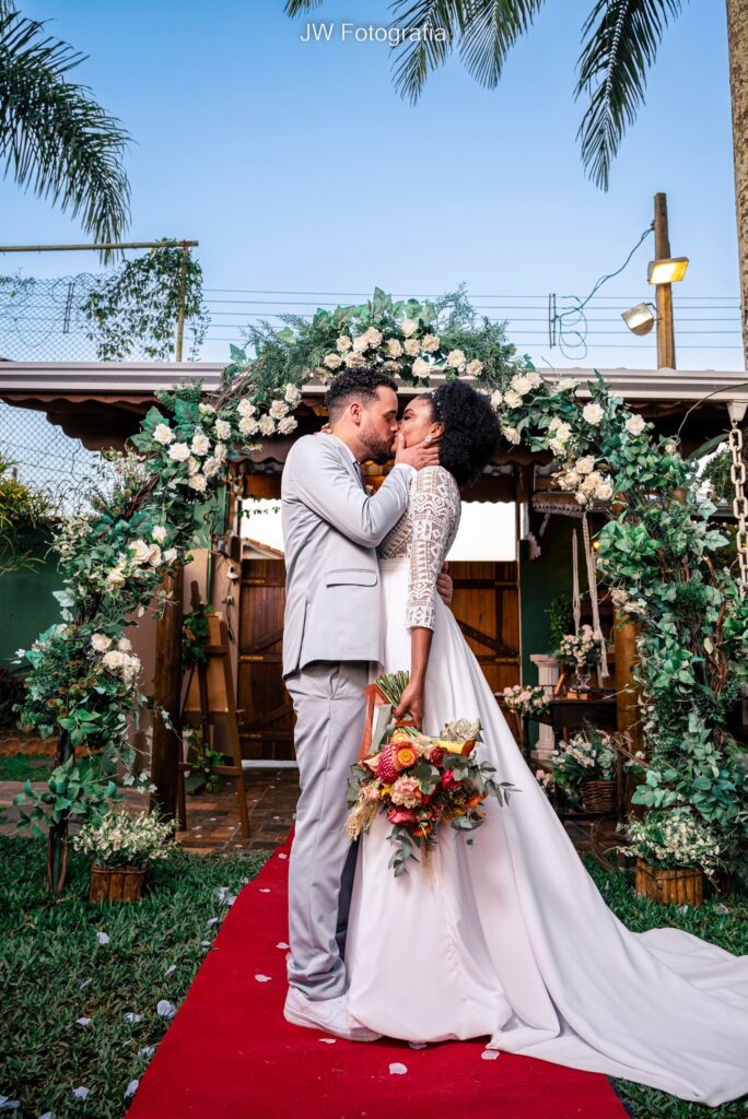 Casar no Jardim das Orquídeas - Casal se beijando diante de um arco de flores rústicas